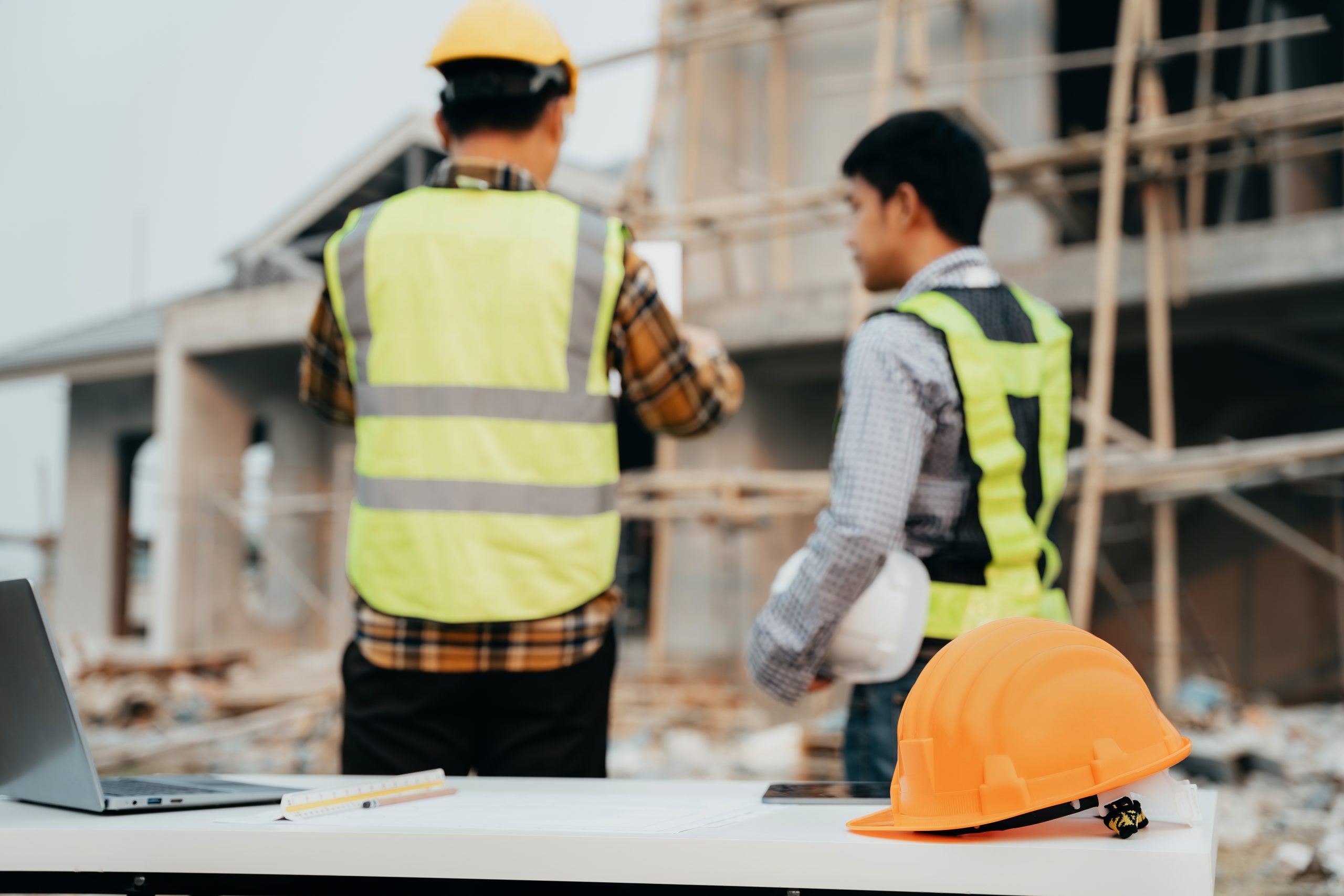 Engineering people and contractor wearing safety helmet on construction site holding blueprint in his hand.